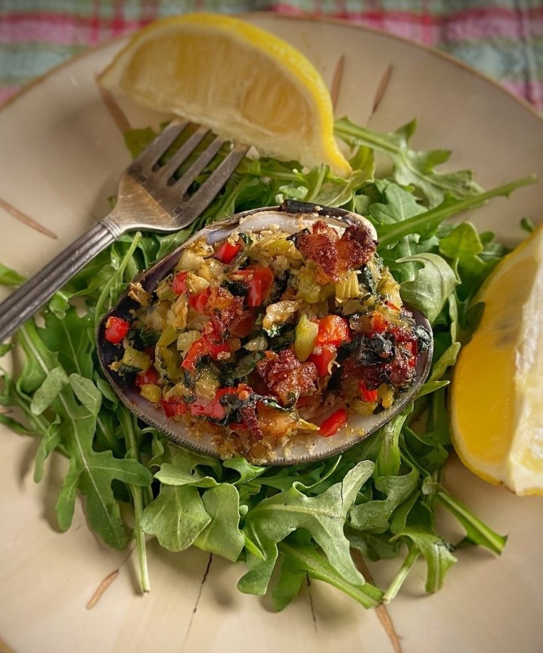 A delicious-looking clam casino on a bed of arugula.