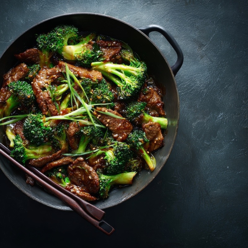 Finished beef and broccoli stir-fry in a wide shallow bowl, glossy oyster sauce