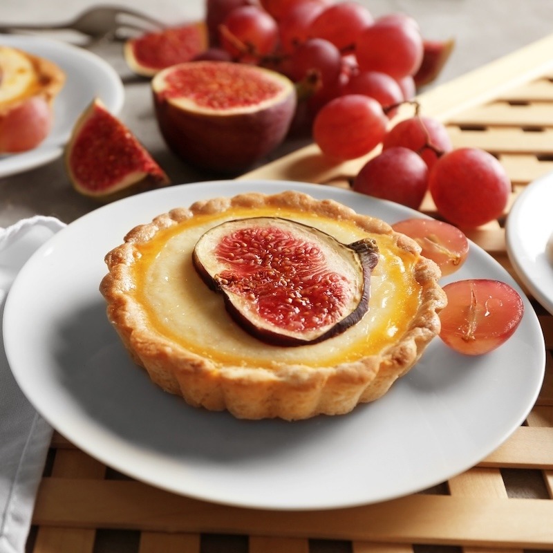 A slice of fig on a tart with sliced grapes