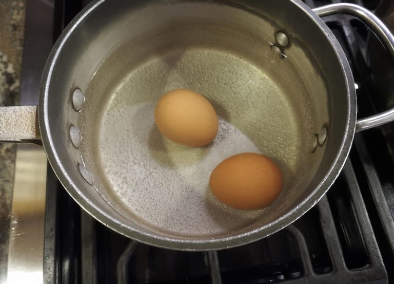 Two eggs simmering in a pot of water