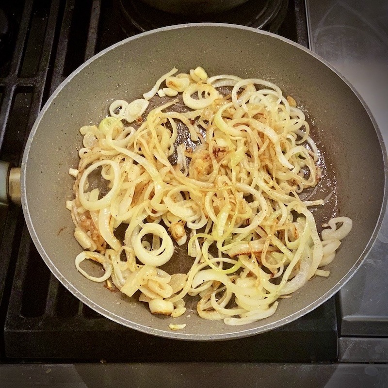 Heated pan caramelizing raw onions.