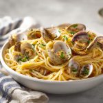 Linguine with clam sauce, served in a wide shallow white bowl.