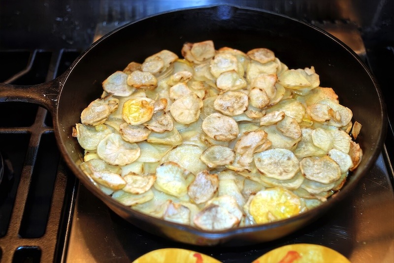 A frying pan with roast cod and scalloped potatoes