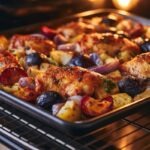 Sheet pan going into the oven, chicken, plums, onions, and potatoes