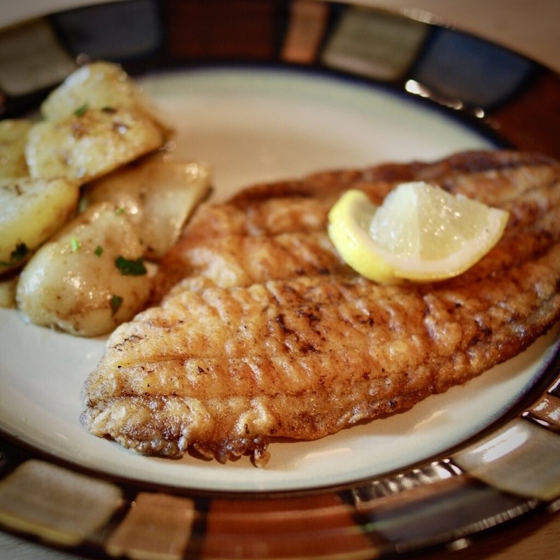 A plate with pan fried flounder with potatoes