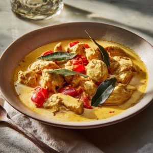 Venezuelan coconut chicken stew served in a shallow ceramic bowl, tender bite-size chicken pieces simmered in a creamy coconut milk sauce.