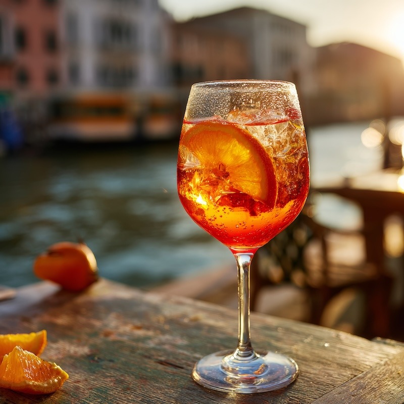 A luminous Aperol Spritz in a large stemmed wine glass filled with ice