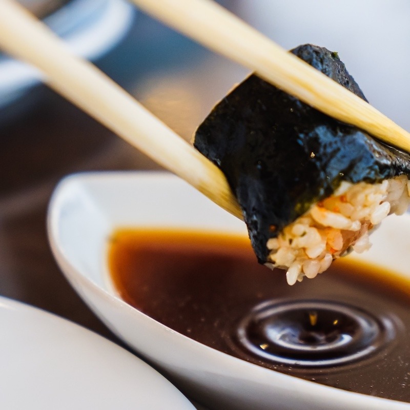 sushi being dipped in soy sauce