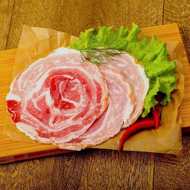Slices of thinly cut pancetta on cutting board