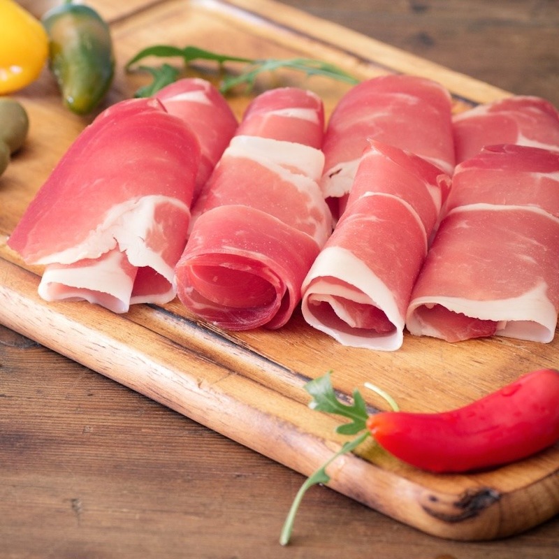 Prosciutto slices rolled and placed on cutting board