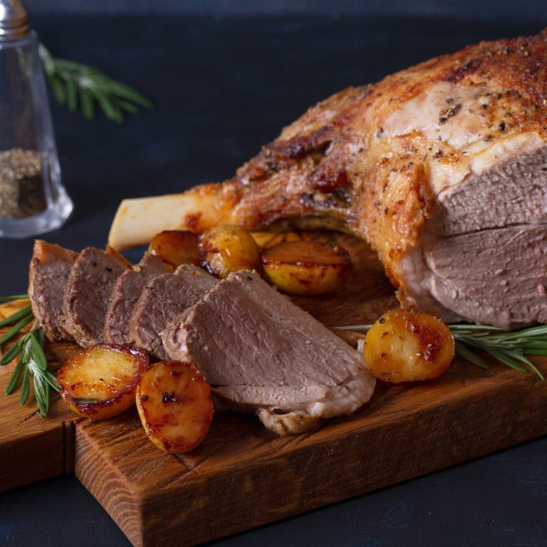 A beautiful bone-in leg of lamb with slices cut from it.