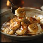 Bananas Foster over vanilla ice cream in a shallow bowl