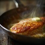 golden-crusted chicken breast searing in a stainless steel skillet