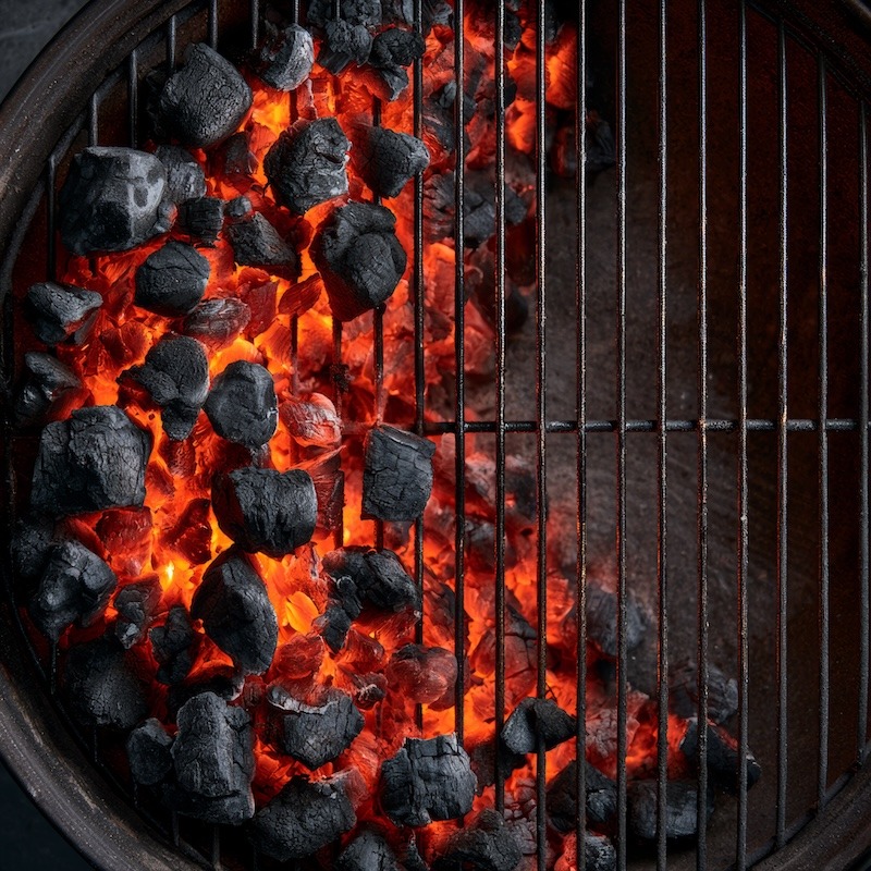 a charcoal grill with coals banked entirely to one side, a clear empty space on the other side