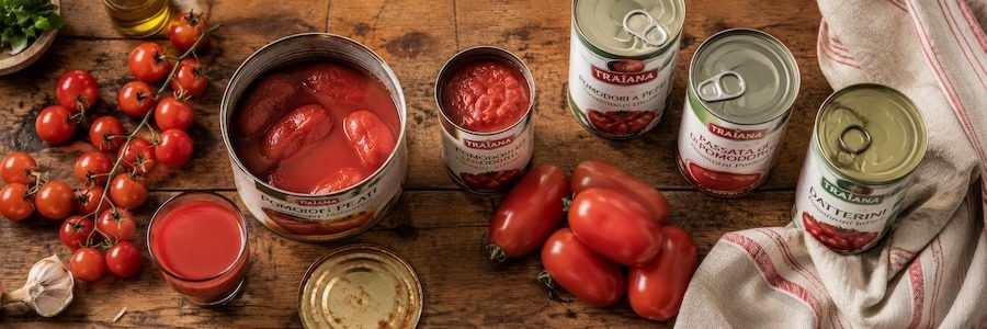 A group of canned tomatoes and fresh ones besides them.