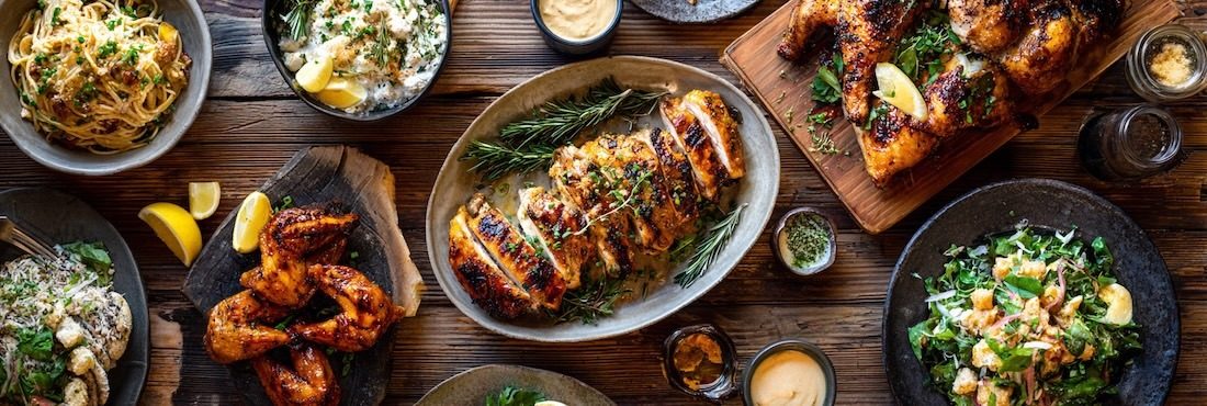 beautifully styled spread of assorted chicken dishes arranged across a rustic wooden table