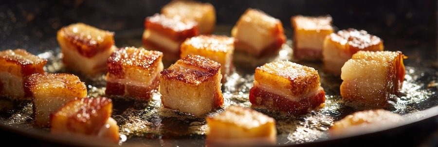 Guanciale cubes sizzling in pan, golden crisp edges